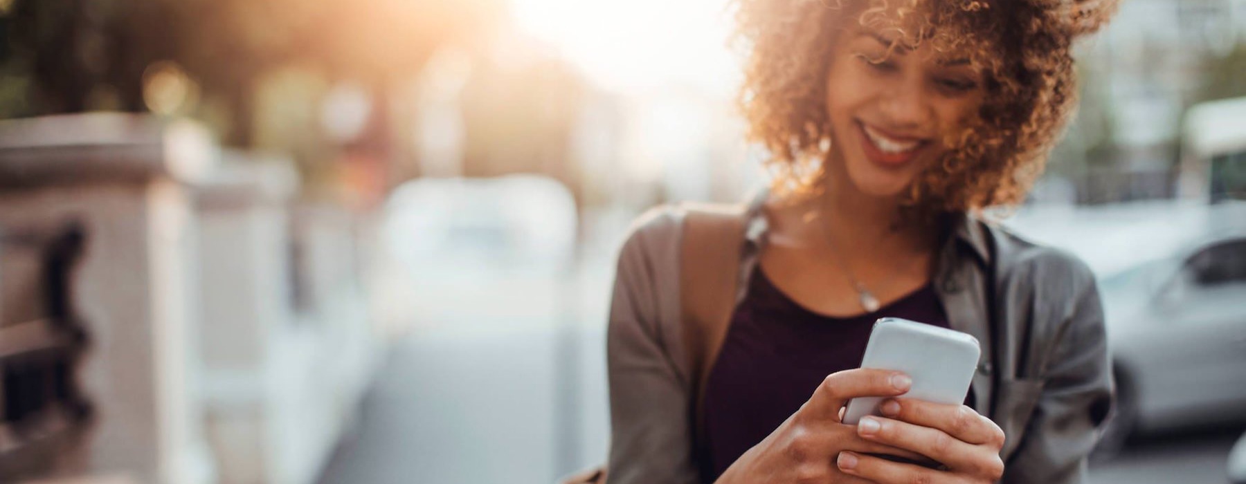 woman texts on her phone as she walks through the city